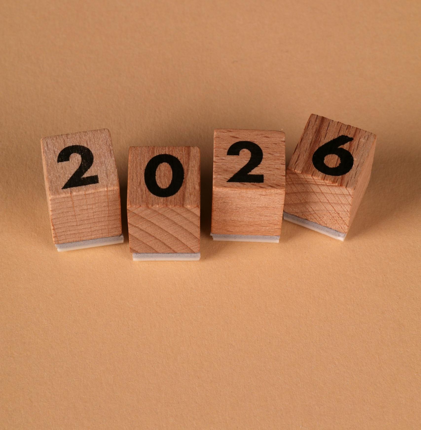 Wooden blocks forming the year 2026 on a warm beige background, symbolizing the new year.
